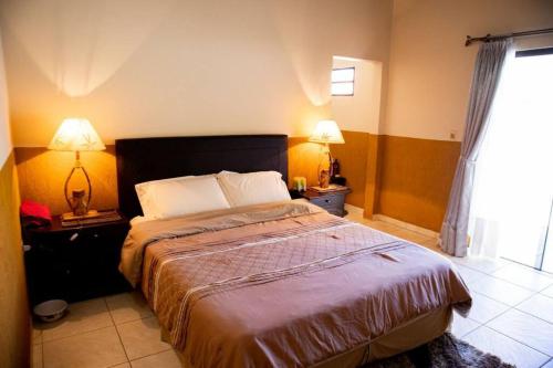 a bedroom with a bed and two lamps and a window at Hermoso Depto con Piscina en Calle Palma Asunción in Asunción