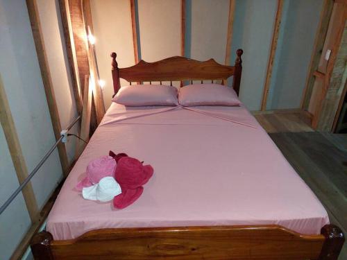 a bed with pink sheets and two roses on it at Casa LalitoHouse cabaña rustica frente al mar. in Pavones
