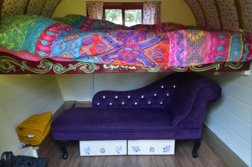 a purple couch sitting under a bed with a blanket at Gypsy Sunrose in Bude