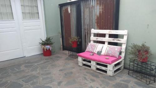 einen Stuhl mit rosa Kissen neben einer Tür in der Unterkunft Aquí te Espero in Tandil