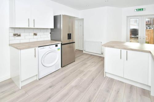 a kitchen with white cabinets and a washer and dryer at Townhouse @ 147 Westminster Street Crewe in Crewe