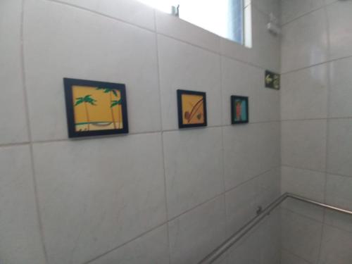 a bathroom with three pictures on the wall and a window at Hotel Kairos in Campina Grande