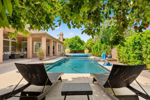 a swimming pool with two chairs and a house at Pool Table, Putting Green Luxury Oasis in Mesa in Mesa