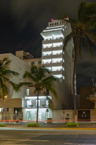 a tall white building with palm trees in front of it at Hawaii Hotel Veracruz in Veracruz