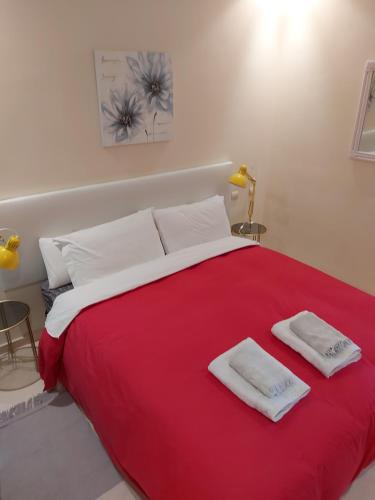 een slaapkamer met een groot rood bed met 2 handdoeken erop bij Estrelicia in Marbella