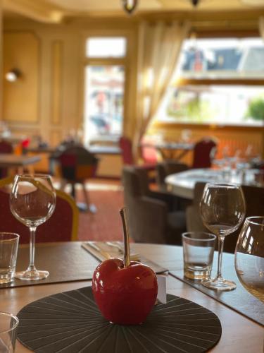a red apple sitting on a table in a restaurant at Les 3 rois by YY in Villers-Bocage