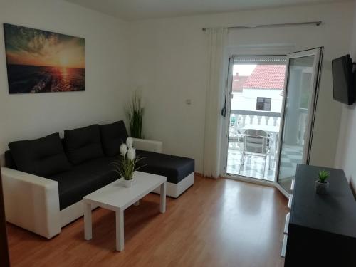 a living room with a black couch and a table at Apartmani kod Rade in Pakoštane