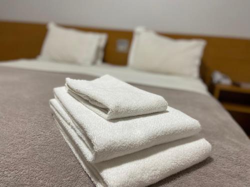 three white towels are stacked on a bed at Hotel Sesi Aruana in Aruanã