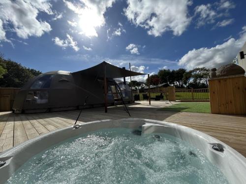 una bañera de hidromasaje en un patio trasero con una tienda de campaña en Sunrise Dome Tent, en Tenby