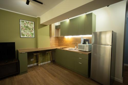 a kitchen with green cabinets and a stainless steel refrigerator at Oliv Residence in Iaşi