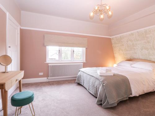 a bedroom with a bed and a desk and a window at Barn Hoppitt Lodge in London