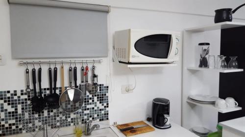 eine Küche mit einer Mikrowelle an der Wand und Küchenutensilien in der Unterkunft Cheap&Chich Studio in Buenos Aires