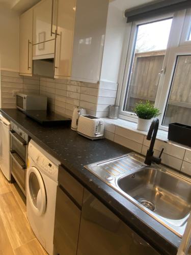 a kitchen with a sink and a washing machine at Lovely and Modern Studio Apartment. in Borehamwood