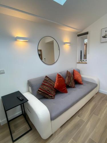 a couch in a room with a mirror on the wall at Lovely and Modern Studio Apartment. in Borehamwood