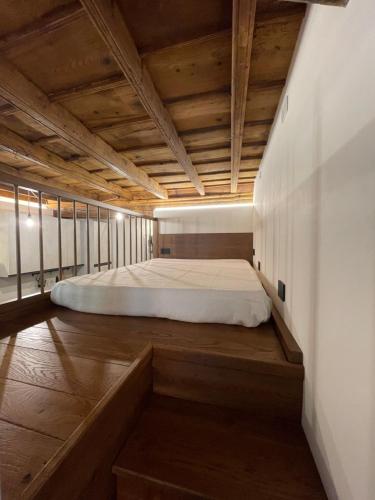 Cama en habitación con suelo y techo de madera en La dimora della Giudecca - 11 en Cuneo
