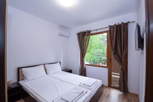 1 dormitorio con cama blanca y ventana en Къща за гости Димови, en Sozopol