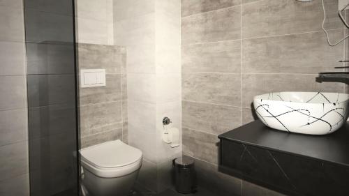 a bathroom with a white toilet and a sink at Hotel Callisto in Pristina