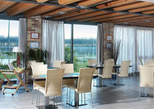 a dining room with tables and chairs and windows at Tenuta Aganis in Palazzolo dello Stella