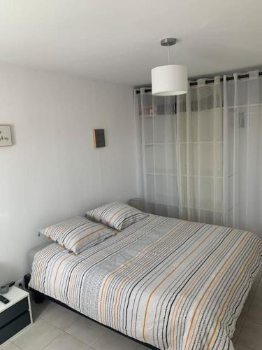 - une chambre avec un lit et une couverture rayée dans l'établissement Appartement 35m2 climatisé a 10 min d’Ajaccio, à Alata