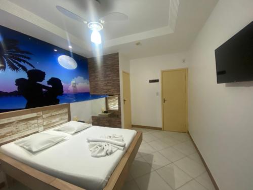 a bedroom with a bed and a flat screen tv at Hotel Bom Gosto in Salvador