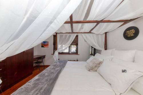 una sala de estar con un gran sofá blanco y cortinas en Sharods Self-catering Guesthouse, en Ciudad del Cabo
