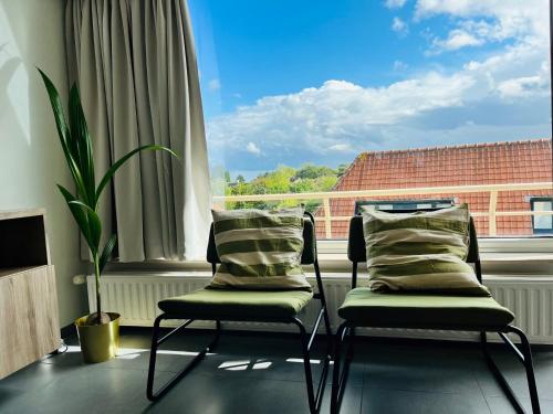 two chairs in a room with a large window at duinpark62: gezellig 3 slaapkamer-appartement inclusief garage in Oostduinkerke