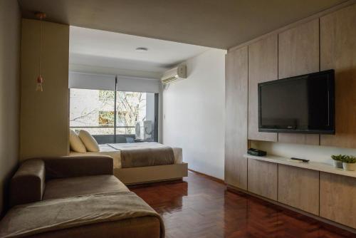 a bedroom with a bed and a flat screen tv at Departamentos Lugar in Cordoba