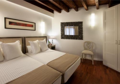 a bedroom with two beds and a chair at Apartamentos Abad Toledo in Toledo