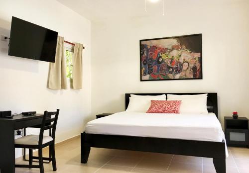 Coral Blanco Hotel في سوسْوا: غرفة نوم بسرير ومكتب وتلفزيون