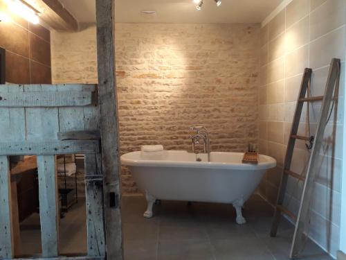 a bathroom with a tub and a brick wall at Au Domaine du Petit Cercoux in Saint-Saturnin-du-Bois
