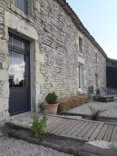 a brick building with a door and a wooden porch at Au Domaine du Petit Cercoux in Saint-Saturnin-du-Bois