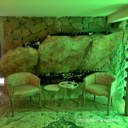 two chairs and a table in front of a stone wall at Casalinho da Azenha - Charm House in Sintra