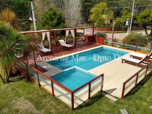 une piscine avec une terrasse en bois et une visière de piscine dans l'établissement Arena de Mar - Dpto D, à Mar de las Pampas