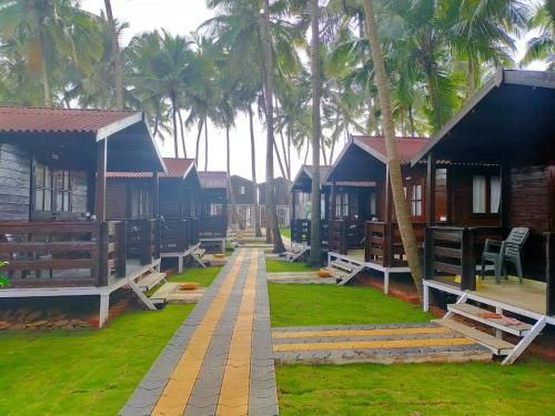 a row of houses with palm trees in the background at Agonda Paradise in Agonda