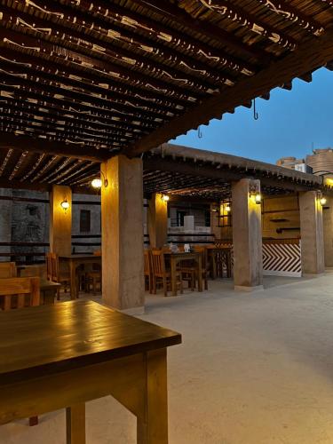 a patio with a wooden table and some tables at Bait Baityn بيت البيتين in Misfāh