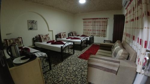 um quarto com três camas e um sofá em Petra Antique House em Wadi Musa