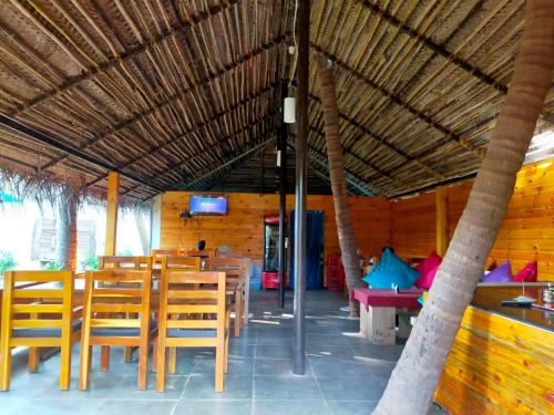 a restaurant with wooden tables and chairs and a tv at Agonda Paradise in Agonda