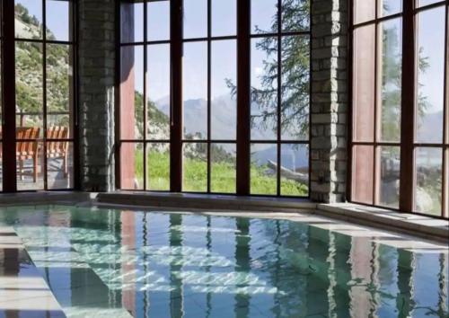a swimming pool with a view of the mountains through windows at Appartement style chalet 5* vue Mont-Blanc - Arc 1950 in Arc 1950
