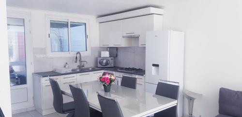 una cocina blanca con mesa y sillas. en MAISON APPARTEMENT TOUT CONFORT À 10mn des plages en Montpellier