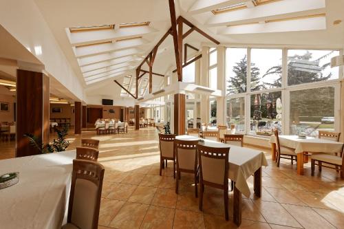 a dining room with tables and chairs and windows at Klaudia's Hotel & Restaurant at Golf Resort, Bač Šamorín in Báč