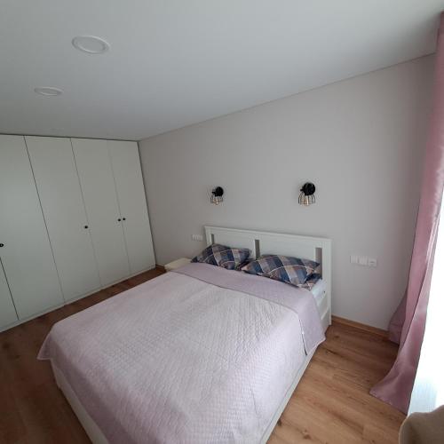 um quarto com uma cama branca e armários brancos em Vytės apartamentai em Kaunas