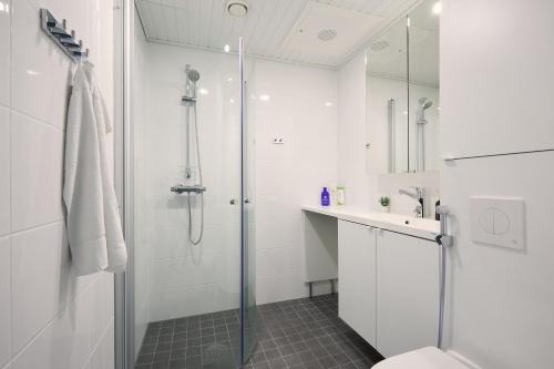 a white bathroom with a shower and a sink at 7.kerroksen huoneisto, Wifi + 24/7 check in in Turku