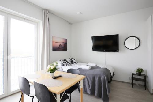 um quarto branco com uma cama, uma mesa e uma televisão em 7.kerroksen huoneisto, Wifi + 24/7 check in em Turku