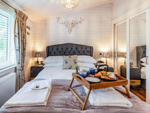 Willington的住宿－Lavender Lodge，一间卧室配有一张床铺,桌子上放着一个食物托盘