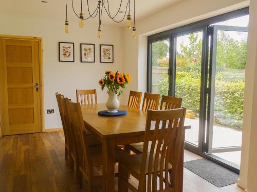 a dining room table with a vase of flowers on it at Woldsend in Moreton in Marsh