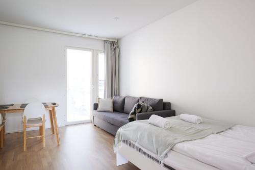 Un dormitorio blanco con una cama y un sofá. en Keskeisen sijainnin uudiskohde, Seamless check-in, Baby crib, en Turku