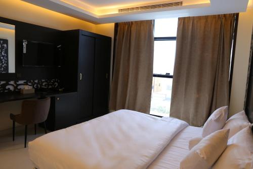 a bedroom with a bed and a large window at ايتن للشقق المخدومه in Taif