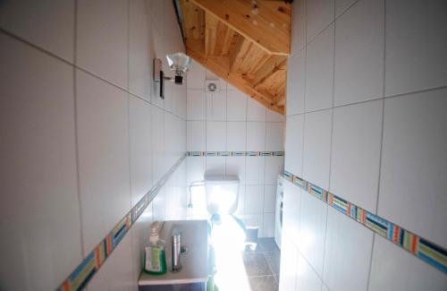 ein Bad mit WC in einem Zimmer mit weißen Fliesen in der Unterkunft Rustic Holiday Villa Upper Qeparo in Himarë