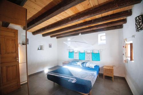ein Schlafzimmer mit einem blauen Bett und einer Holzdecke in der Unterkunft Rustic Holiday Villa Upper Qeparo in Himarë