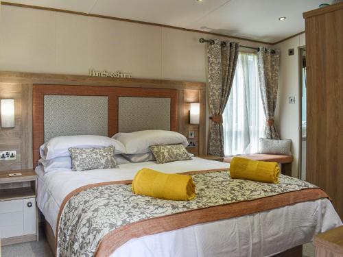 a large bedroom with a large bed with yellow pillows at Deer Glade Lodge in Landford